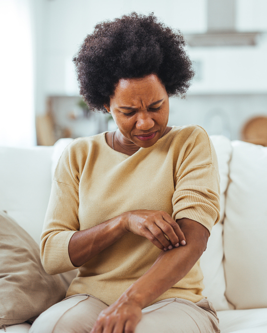 Woman Scratching Arm Due to Skin Irritation at Home Eczema Treatments Near Me in Verona & Rutherford | Geria Dermatology in New Jersey