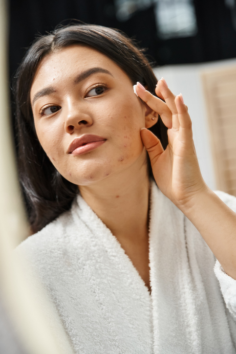 A young woman practicing her skincare routine in a serene morning setting at home Acne Treatments Near Me in Verona & Rutherford | Geria Dermatology in New Jersey